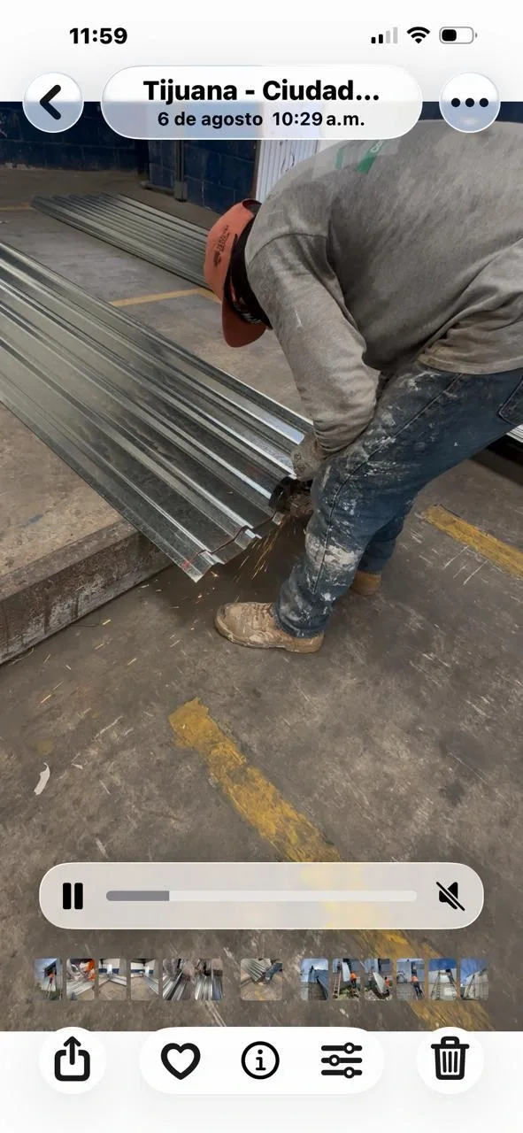 Trabajador cortando una lámina acanalada con una herramienta eléctrica en un taller.